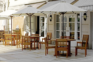 Wooden cafe tables and chairs with parasols line the courtyard, which is designed mainly in white