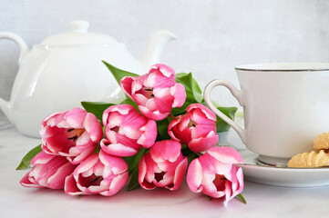 Pink tulips on table with teacup and teapot - spring teatime