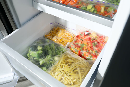 Plastic bags with different frozen vegetables in refrigerator
