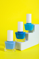 Stylish presentation of nail polishes in bottles on yellow background