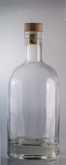 A clear glass bottle with a cork top against a light background. Simple, versatile, and ready to be filled.