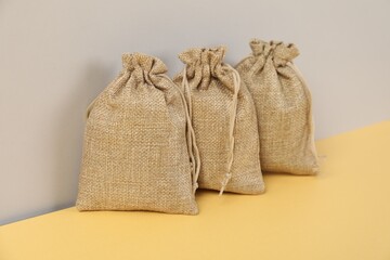 Three natural burlap bags on color background