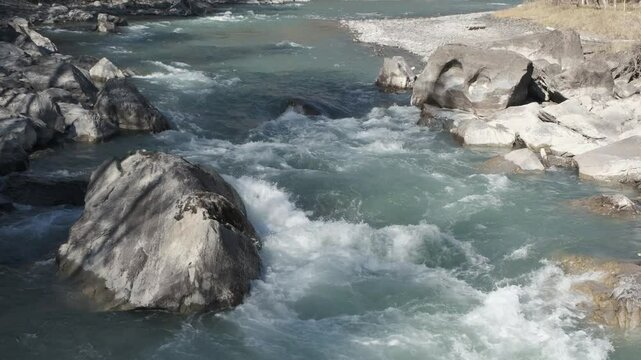 Fast moving stream of seething mountain river runs along stone banks. Altai