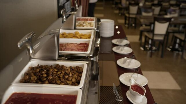 Hotel breakfast buffet displaying variety of fresh, delicious morning cuisine in chafing dishes, presenting gourmet selection of eggs, bacon, vegetables on restaurant table