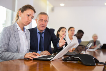 Obraz premium Mature businessman prompts and helps businesswoman during a business meeting