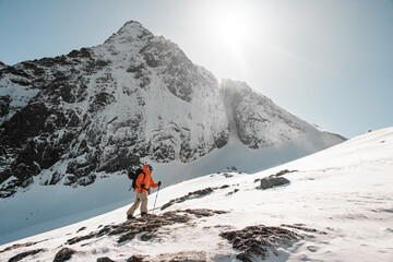 Skier in an orange jacket is skiing down a mountain slope, looking ahead