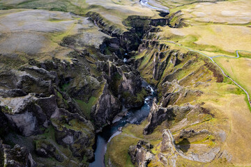 Breathtaking aerial drone view of a serene river winding through a majestic Fjadrargljufur Canyon in Iceland