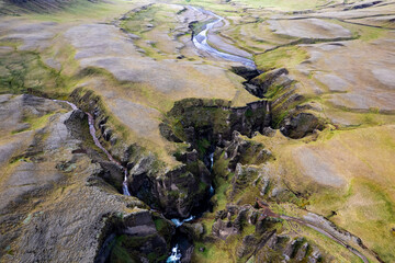 Breathtaking aerial drone view of a serene river winding through a majestic Fjadrargljufur Canyon in Iceland