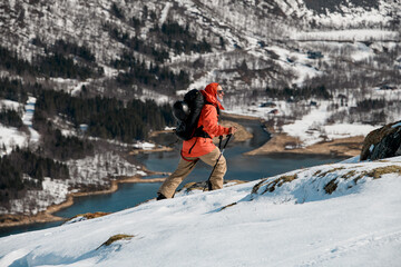 Energetic skier climbs a gentle mountain slope with poles in his hands