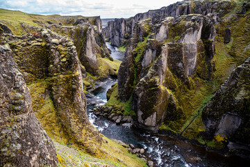 Breathtaking aerial drone view of a serene river winding through a majestic Fjadrargljufur Canyon in Iceland