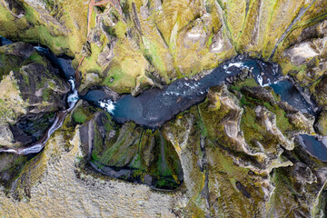 Breathtaking aerial drone view of a serene river winding through a majestic Fjadrargljufur Canyon in Iceland