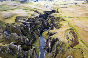 Breathtaking aerial drone view of a serene river winding through a majestic Fjadrargljufur Canyon in Iceland