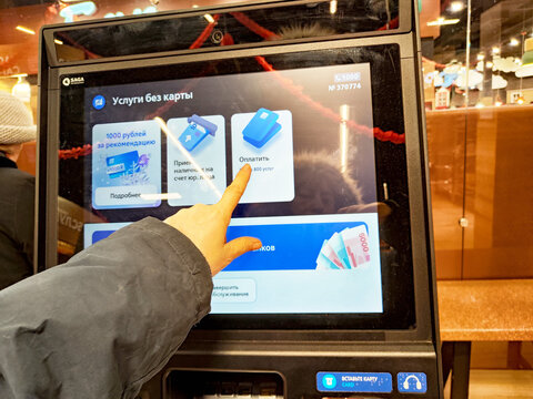 Kirov, Russia - December 28, 2024: User interacting with VTB ATM of VTB Bank in a modern urban setting during daytime for cash withdrawal