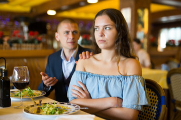 Young unhappy couple quarreling during dinner at restaurant