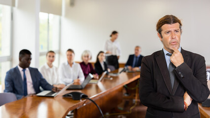 Portrait of successful businessman in front of team of businessmen in a meeting room