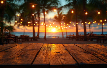 A wooden table with a view of the ocean and palm trees. The table is lit up with lights and the sun is setting in the background
