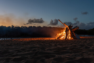 A large bonfire on the beach at sunset