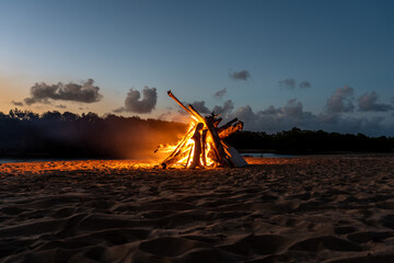 A large bonfire on the beach at sunset