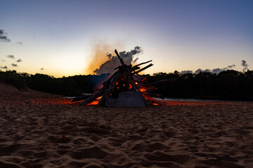 A large bonfire on the beach at sunset