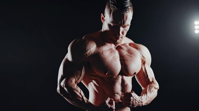 Muscular bodybuilder flexing defined muscles under dramatic spotlights, revealing powerful physique with intense focus and strength against dark background