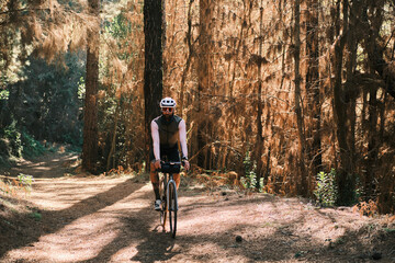 Fototapeta premium A cyclist rides through a sun-dappled forest path. The scene evokes a sense of adventure and tranquility. Perfect for travel, active lifestyle, and nature-themed projects.