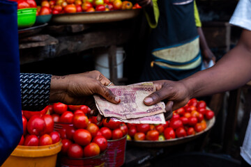 Young African market woman collecting cash for payments in an open market