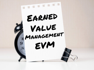 Earned Value Management EVM header on white note paper background alarm clock