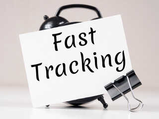 Fast Tracking text meaning on white note paper background alarm clock