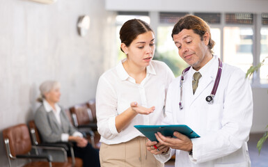 Fototapeta premium Female patient consults with male doctor about diagnosis and treatment