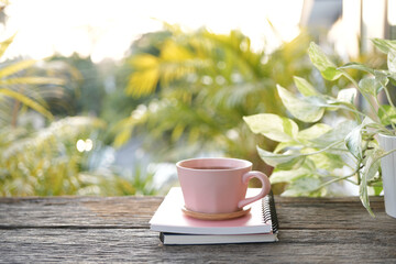 Pink cup and pink pen and notebook on weathered blue wooden table pastel tones, cozy work space