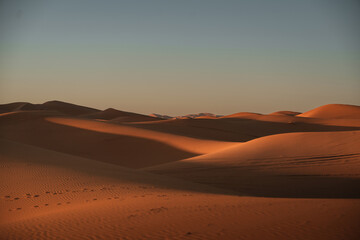 Stunning view of the warm sunlight casting long shadows over the beautiful erg chebbi dunes in merzouga desert, morocco, creating a captivating landscape