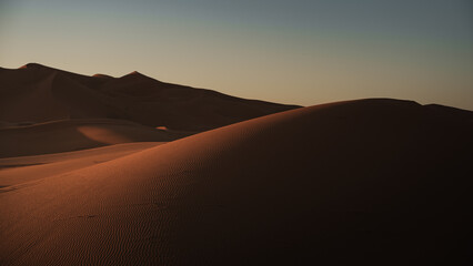 Stunning view of the sun setting over the erg chebbi dunes in the sahara desert near merzouga, morocco
