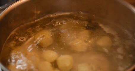 In a vibrant kitchen setting, dough balls stuffed with cheese are immersed in boiling water within a steel pan, capturing the essence of culinary artistry. This footage celebrates homemade cuisine.