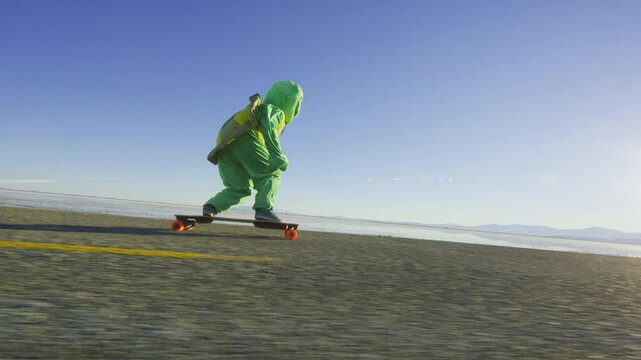 Cinematic silhouette of person in frog costume riding a longboard on desert road with sun flare, low shot