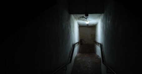 Dark old staircase in a bomb shelter with worn steps and dim lighting creates mysterious and eerie atmosphere ideal for historical abandoned, or post apocalyptic scenes or urban exploration concepts