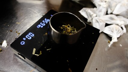 weighing herbal tea on digital scales with metal container fresh herbs green tea leaves organic healthy ingredients for tea making natural remedy herbal tea preparation for wellness and relaxation