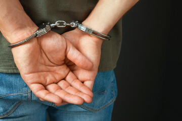 Man in metal handcuffs on black background, closeup