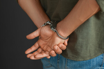 Man in metal handcuffs on black background, closeup