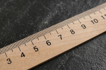 One wooden ruler on black table, closeup