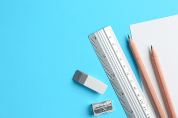 Flat lay composition with ruler and other stationery on light blue background, space for text