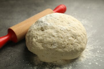 Fresh dough and rolling pin on grey table, closeup