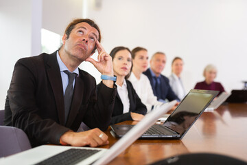 Bored businessman looking at ceiling at business meeting in meeting room