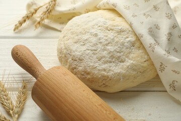 Fresh dough, rolling pin and spikes on white wooden table, closeup
