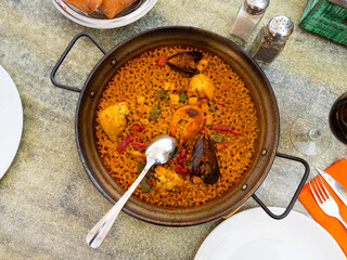 Authentic chicken and seafood paella with creamy lemon sauce served in paella pan