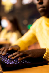 African american student engaged in essay writing at a library table, completing homework school assignments and demonstrating academic skills. Scholar girl writes ideas on her laptop. Close up.