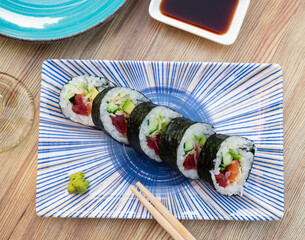 Traditional thick sushi roll futomaki filled with salmon, tuna, avocado, surimi and cucumber