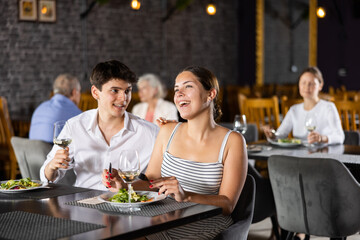 Young positive man and woman people communicate in restaurant during dinner. Guy and girl have date in cafe, eat Oriental cuisine, drink wine tasting