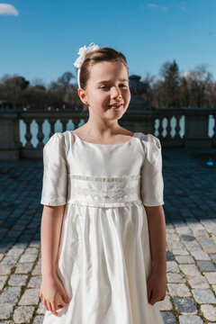 Young girl in white First Communion dress in sunny outdoors