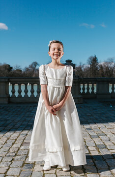 Girl in first communion dress posing outdoors on sunny day