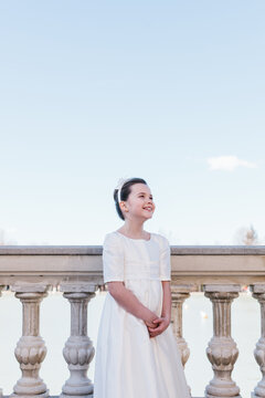 Young girl in First Communion dress smiling outdoors